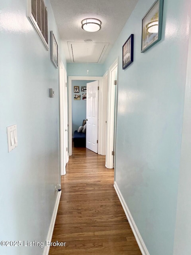 corridor with hardwood / wood-style flooring and a textured ceiling