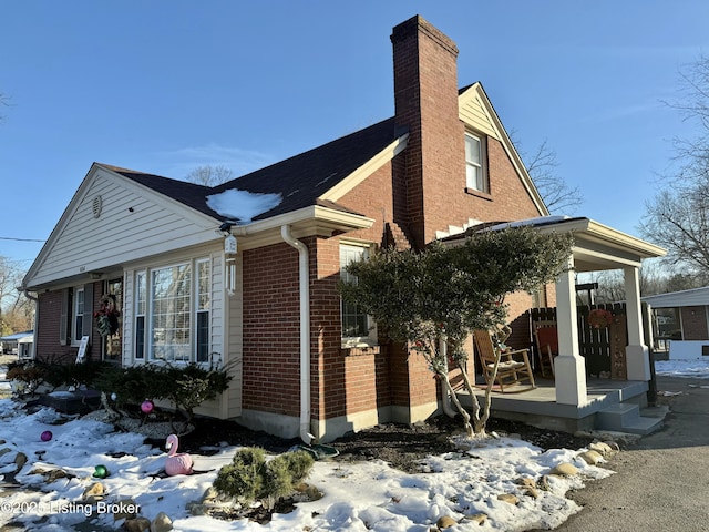 snow covered property with covered porch