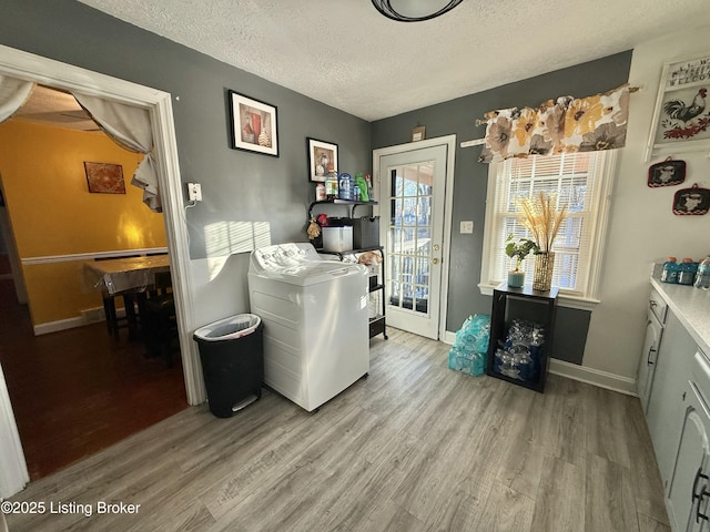 washroom featuring washer / clothes dryer, a textured ceiling, and light hardwood / wood-style flooring