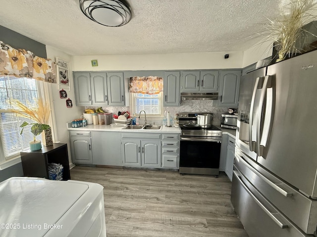 kitchen featuring sink, gray cabinetry, backsplash, stainless steel appliances, and light hardwood / wood-style floors