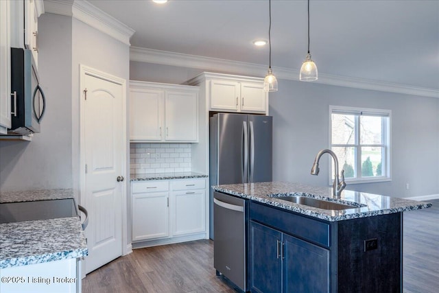 kitchen featuring pendant lighting, sink, appliances with stainless steel finishes, white cabinetry, and a center island with sink