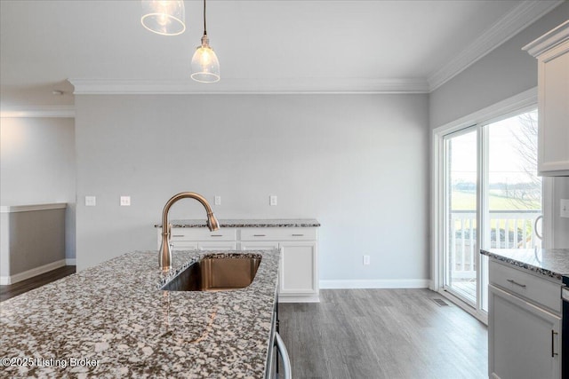 kitchen with decorative light fixtures, sink, white cabinets, ornamental molding, and light stone countertops