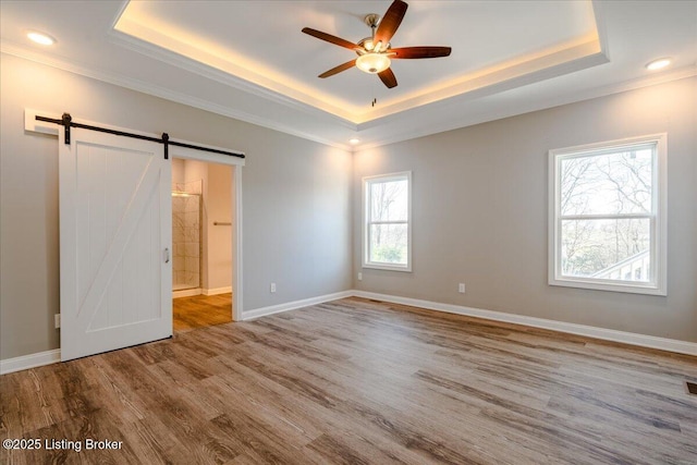 unfurnished bedroom with multiple windows, a raised ceiling, ceiling fan, and ensuite bathroom