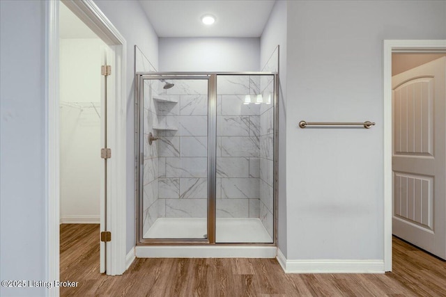 bathroom with hardwood / wood-style flooring and a shower with shower door