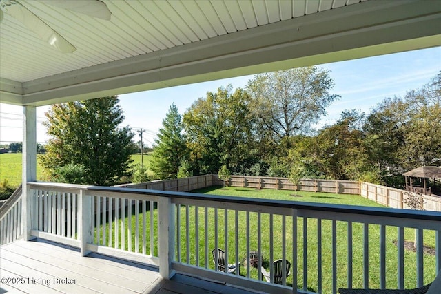 wooden deck with ceiling fan and a lawn