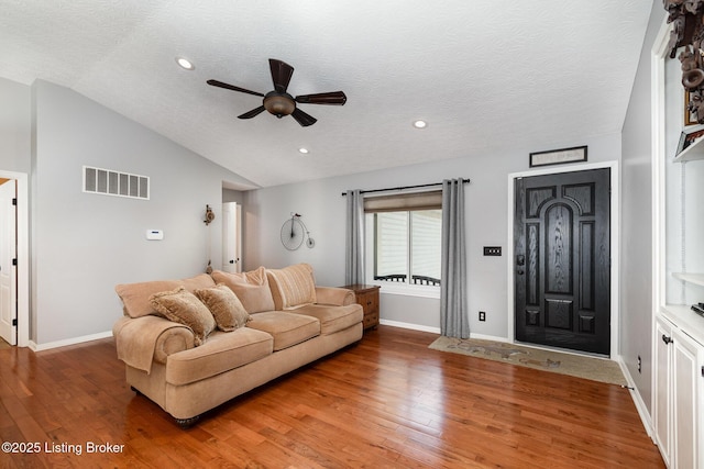 living room with lofted ceiling, ceiling fan, wood-type flooring, and a textured ceiling