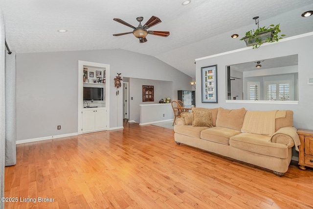 living room with vaulted ceiling, ceiling fan, light hardwood / wood-style floors, and a textured ceiling