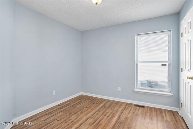 empty room with hardwood / wood-style flooring and a textured ceiling