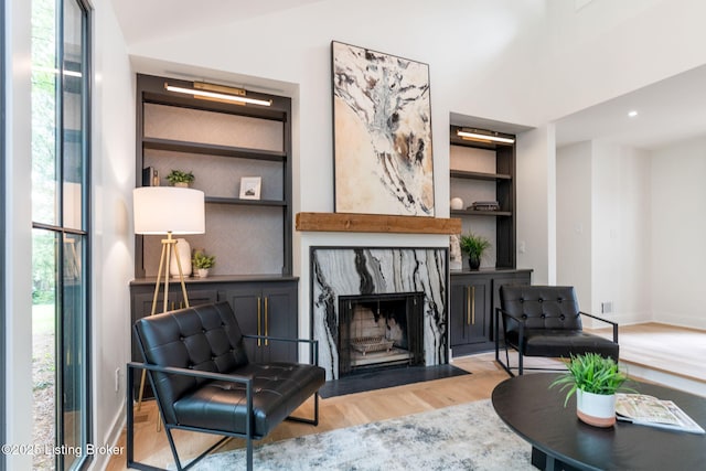 living room featuring a high end fireplace, built in features, and light wood-type flooring