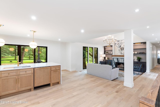 kitchen featuring hanging light fixtures, a premium fireplace, dishwashing machine, and light hardwood / wood-style floors