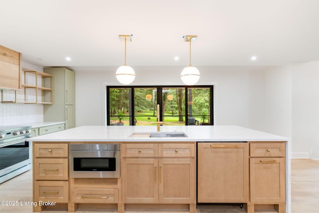 kitchen with backsplash, hanging light fixtures, a center island with sink, stainless steel range with electric cooktop, and light brown cabinets