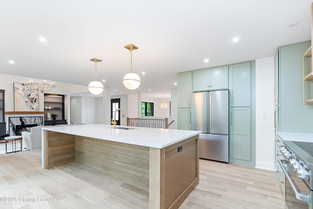 kitchen featuring sink, hanging light fixtures, light hardwood / wood-style flooring, an island with sink, and stainless steel appliances