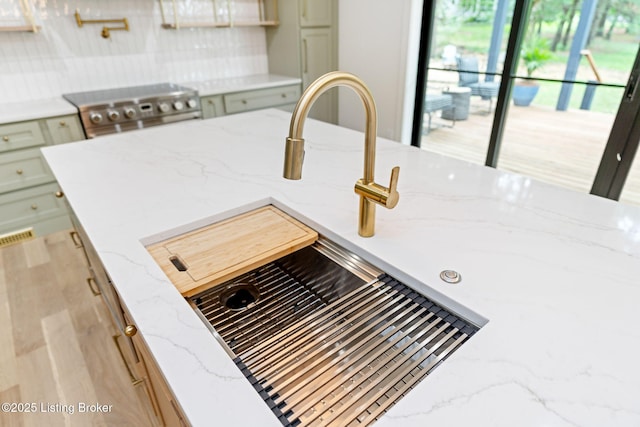 kitchen with light stone countertops, sink, and backsplash