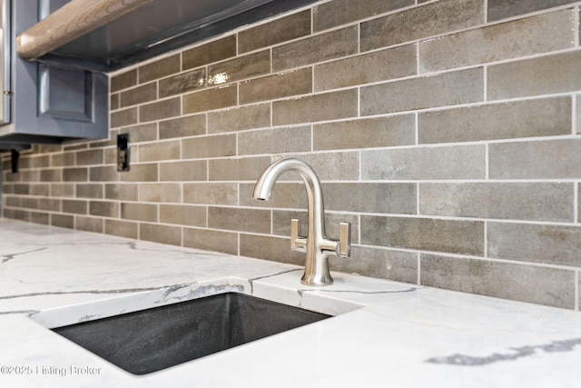 details featuring light stone countertops, sink, and backsplash