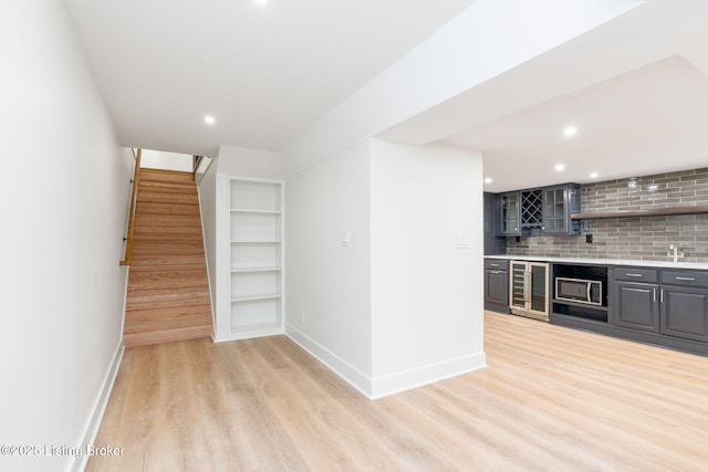 kitchen with built in features, sink, wine cooler, backsplash, and light hardwood / wood-style flooring