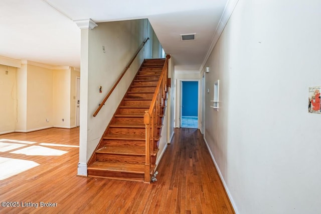 stairs with crown molding and hardwood / wood-style flooring