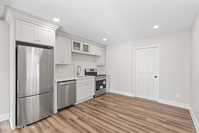 kitchen with sink, light hardwood / wood-style flooring, white cabinets, and appliances with stainless steel finishes