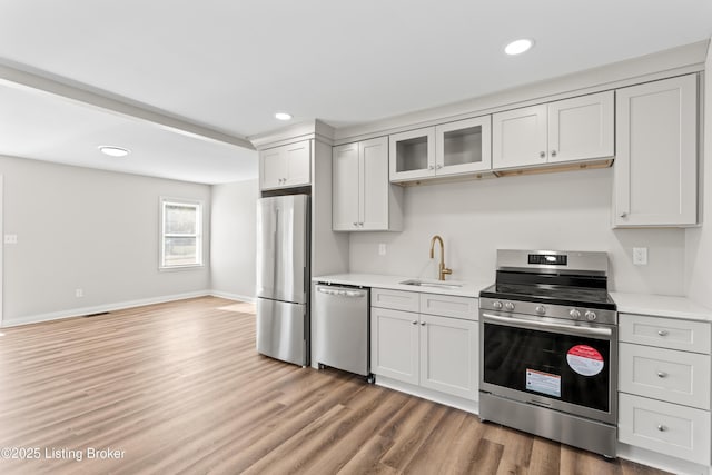 kitchen featuring stainless steel appliances, hardwood / wood-style flooring, sink, and white cabinets