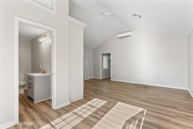 interior space featuring lofted ceiling, light wood-type flooring, and a wall unit AC