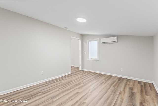 spare room with a wall mounted air conditioner and light hardwood / wood-style flooring
