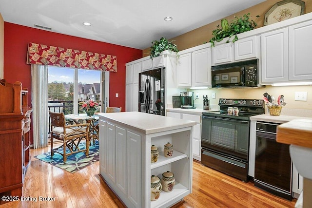 kitchen with black appliances, light hardwood / wood-style floors, white cabinets, and a kitchen island