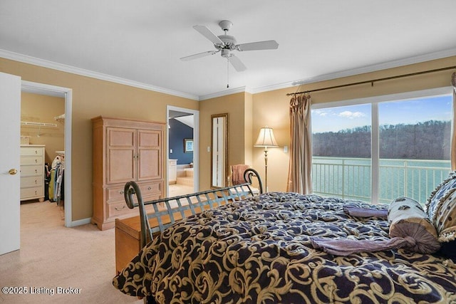 carpeted bedroom with a water view, a walk in closet, ornamental molding, a closet, and ceiling fan