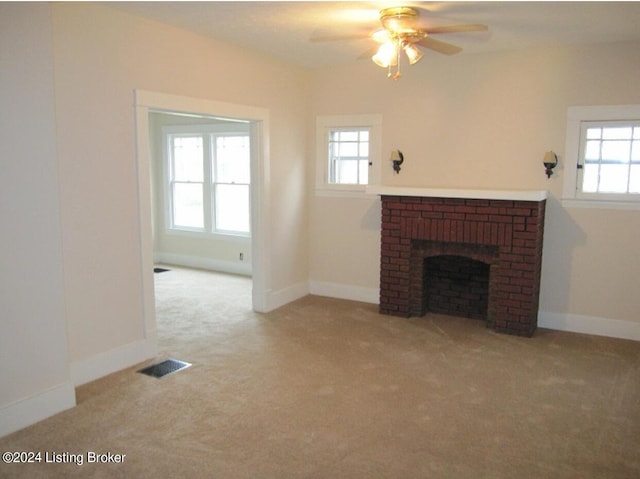 unfurnished living room with ceiling fan, a fireplace, and light carpet