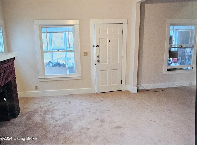 carpeted foyer with a brick fireplace