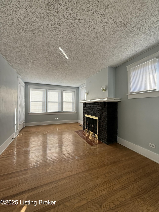 unfurnished living room with a brick fireplace, wood-type flooring, and a textured ceiling