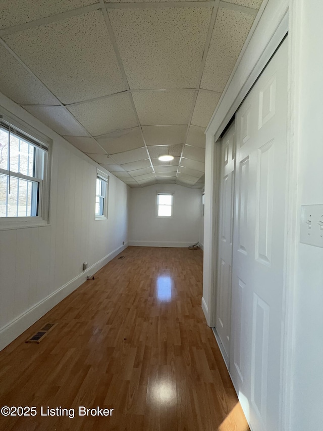 basement with a paneled ceiling and wood-type flooring