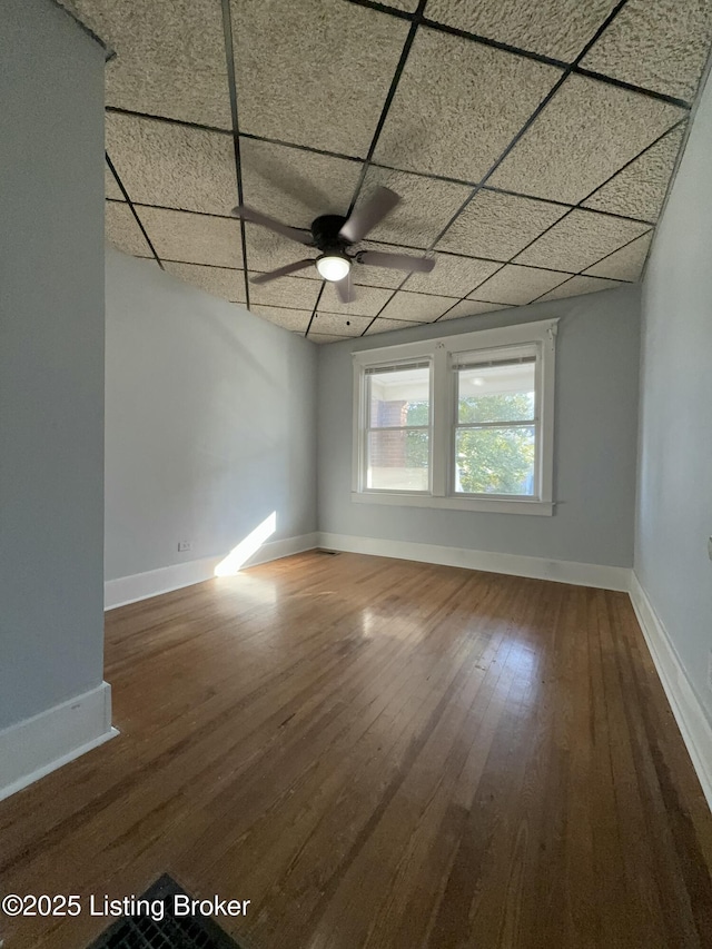 unfurnished room with ceiling fan, hardwood / wood-style floors, and a drop ceiling