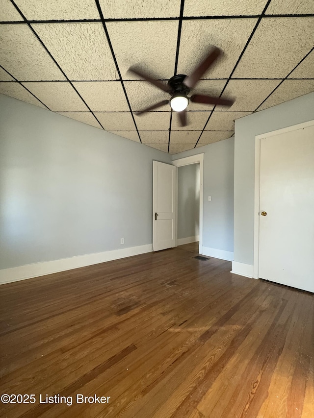 spare room with hardwood / wood-style flooring, ceiling fan, and a drop ceiling