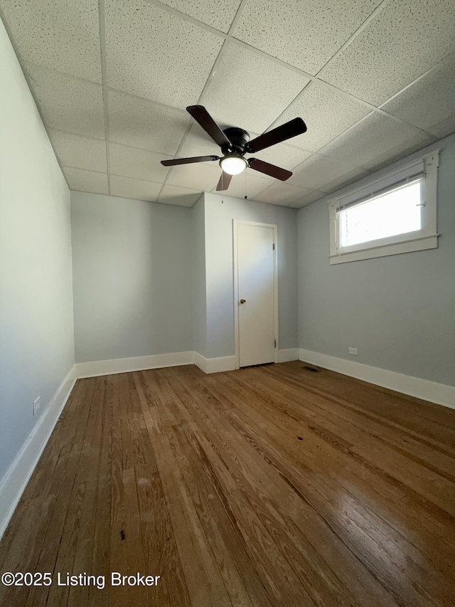 unfurnished room with a drop ceiling, hardwood / wood-style floors, and ceiling fan