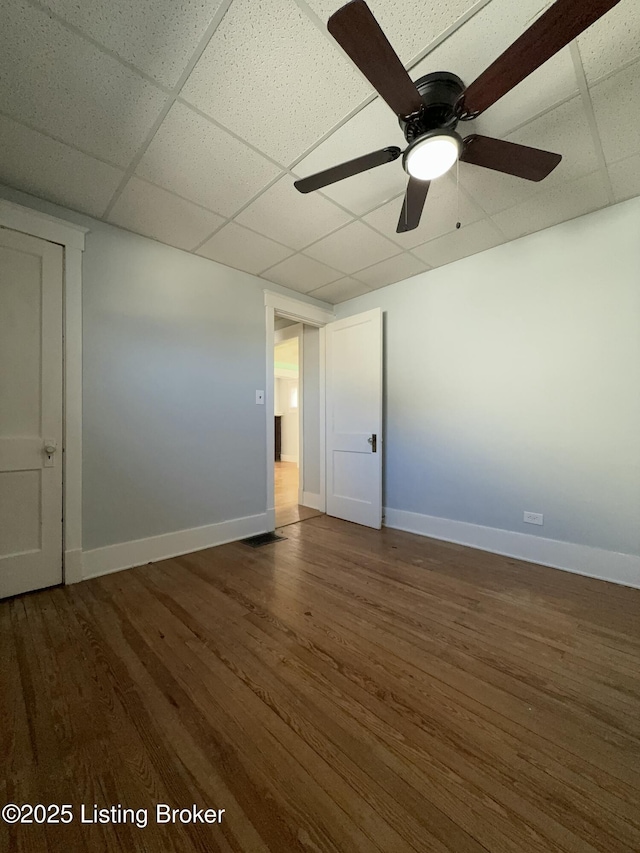 spare room featuring ceiling fan, dark hardwood / wood-style floors, and a drop ceiling