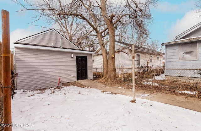 snow covered back of property featuring an outdoor structure