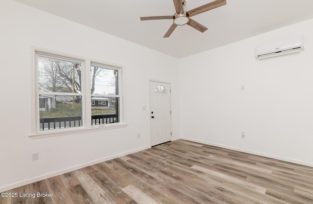 spare room featuring hardwood / wood-style floors, an AC wall unit, and ceiling fan