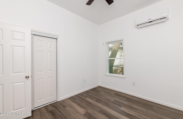 unfurnished bedroom with an AC wall unit, dark wood-type flooring, ceiling fan, and a closet