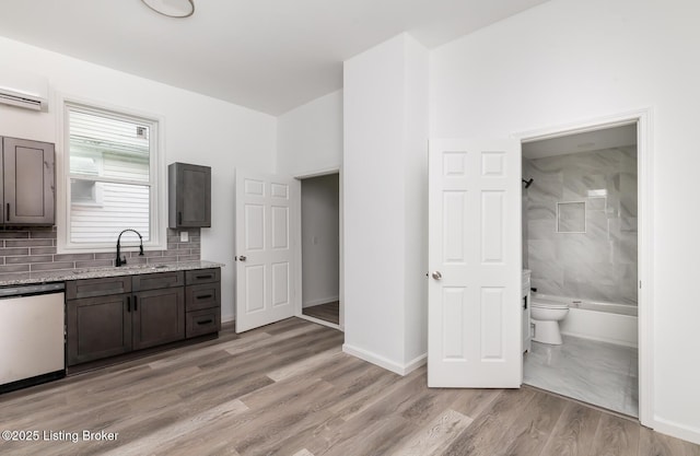 kitchen with sink, light stone counters, dark brown cabinets, light hardwood / wood-style flooring, and dishwasher