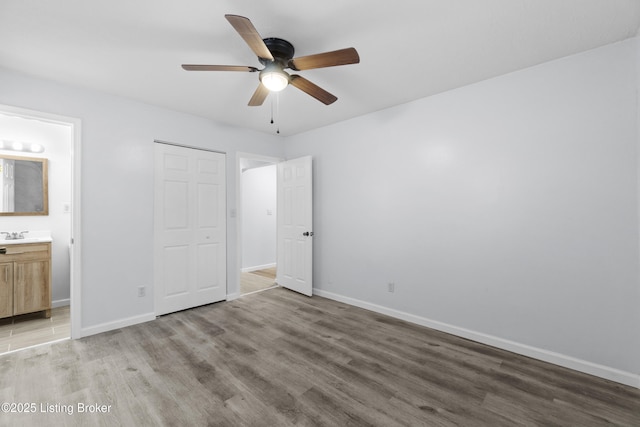 unfurnished bedroom with connected bathroom, sink, a closet, ceiling fan, and hardwood / wood-style floors