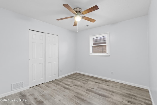 unfurnished bedroom featuring light hardwood / wood-style flooring, ceiling fan, and a closet