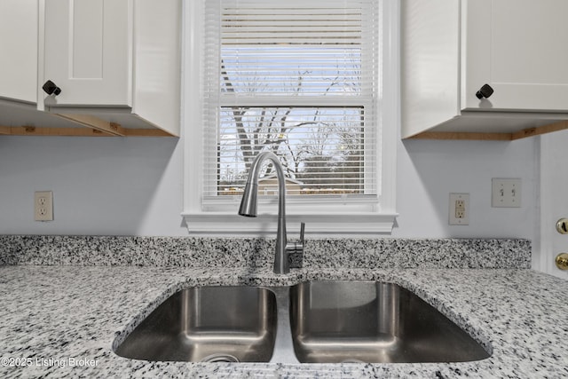 room details featuring white cabinetry, sink, and light stone countertops