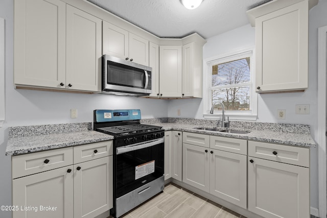 kitchen featuring white cabinetry, sink, stainless steel appliances, light stone countertops, and a textured ceiling