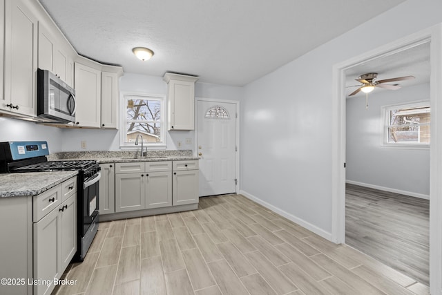 kitchen featuring white cabinetry, sink, light stone counters, stainless steel appliances, and a textured ceiling