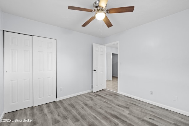 unfurnished bedroom featuring light hardwood / wood-style floors, ceiling fan, and a closet