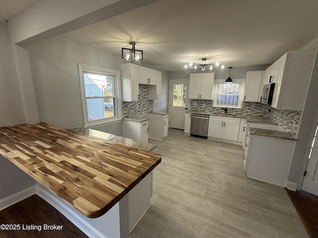 kitchen featuring sink, tasteful backsplash, hanging light fixtures, stainless steel appliances, and white cabinets