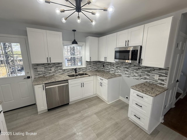 kitchen featuring sink, white cabinetry, hanging light fixtures, appliances with stainless steel finishes, and backsplash