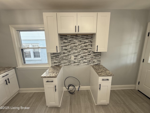 kitchen featuring stone counters, white cabinets, and decorative backsplash