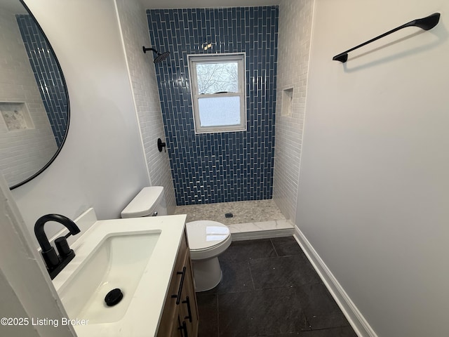 bathroom with tiled shower, vanity, toilet, and tile patterned floors