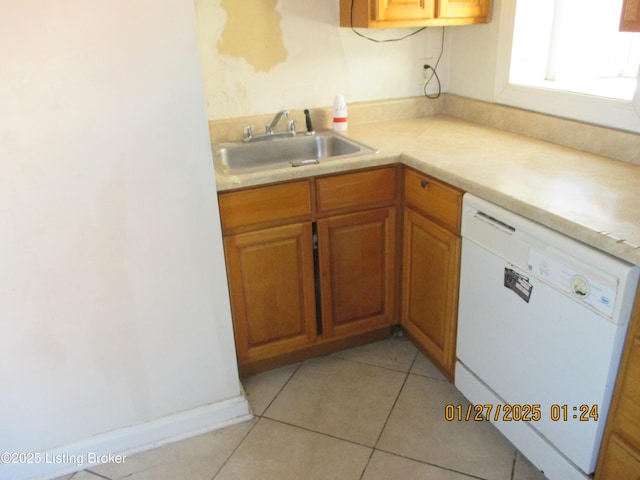 kitchen featuring white dishwasher, sink, and light tile patterned floors