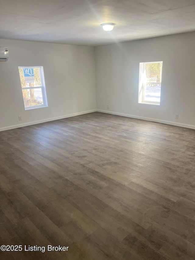 unfurnished room featuring dark wood-type flooring and a wall mounted AC